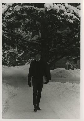 Student carying books on a snow covered walkway.