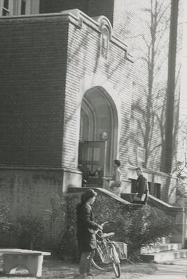 Woman with bike in front of building.