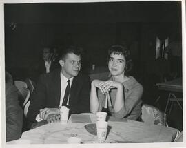 Man looking at a woman at a table, no date.