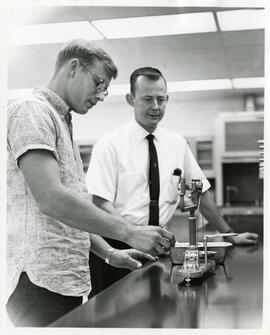 Pair looking at equipment, 1966