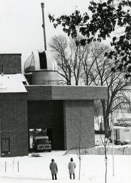 Two people watch as the observatory dome is installed, 1980.