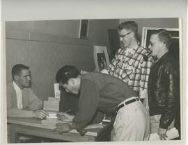 People signing a sheet of paper, no date.