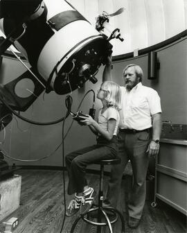 Pair looking into large telescope