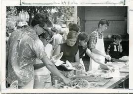 Students getting watermelon from table, 1950-1970