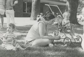 Woman sitting on grass with two kids.