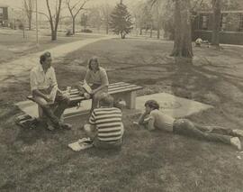 Group sitting on a bench and grass.