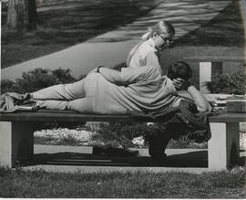 Two students lounging outside on bench, 1969.