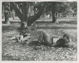 Two people sitting on grass.