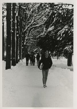 Student carying books on a snow covered walkway.