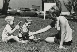 Woman with two kids on grass.