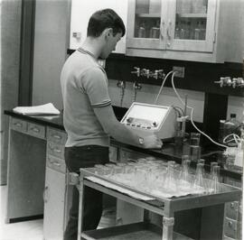 Student standing next to tray of many beakers