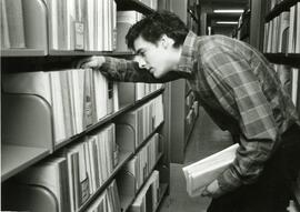 Student looking for books in the stacks, 1987.