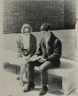 Two students sitting on stone bench, 1960.