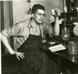 Student in apron holding beaker