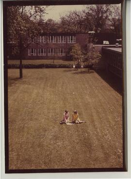 Two woman studying on grass.