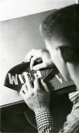 Student decorating freshman beanie, 1950-1970.