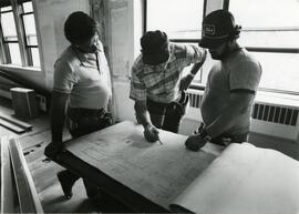 Three people looking at blueprints for observatory
