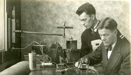Two people in front of a desk with equipment