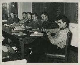 Group sitting in front of chalkboard, no date.