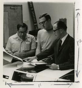 Three men reviewing documents at a table.