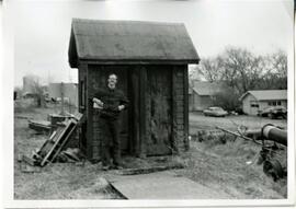 Prescott: railroads and depots, George Joyce standing in front of old out house, undated